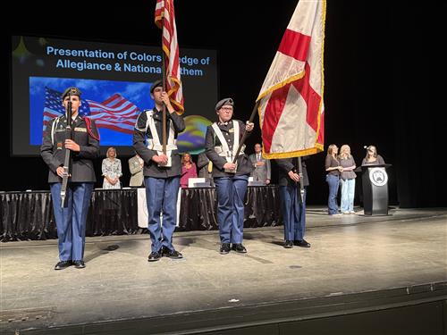 Institute Day color guard on stage with board members in background